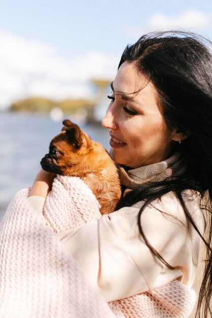 Jeune fille brune tenant un petit chien brun se bouchent