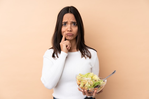 Jeune fille brune tenant une salade sur fond isolé et à l'avant