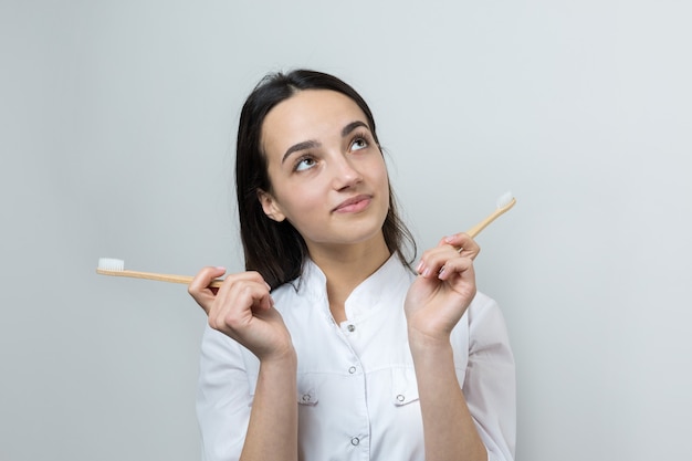 Une jeune fille brune tient une brosse à dents écologique dans ses mains