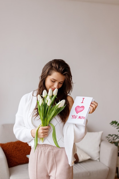 Jeune fille avec une carte postale et des tulipes sur la journée internationale de la femme