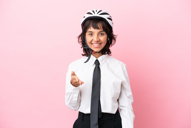 Jeune fille avec un casque de vélo isolé sur fond rose se serrant la main pour conclure une bonne affaire