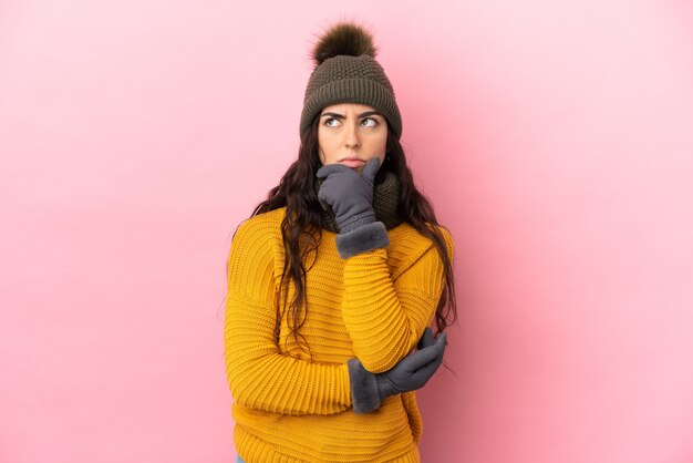 Jeune fille caucasienne avec chapeau d'hiver isolé sur fond violet ayant des doutes