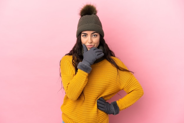 Jeune fille caucasienne avec chapeau d'hiver isolé sur fond violet pensant