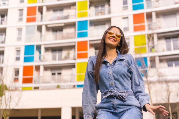 Jeune fille caucasienne avec un cow-boy singe et un sac noir Profiter de la ville en vacances un style de vie de jeune fille assise dans une maison colorée avec des lunettes de soleil orange