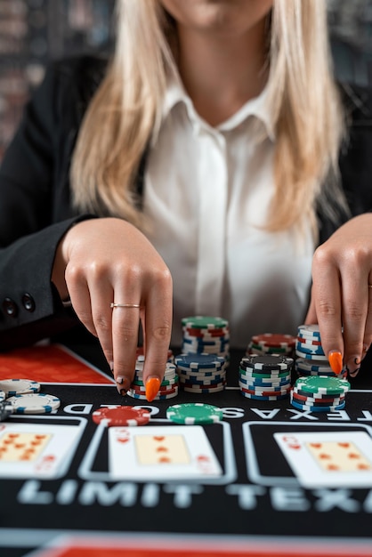Jeune fille caucasienne dans un casino jouant au poker avec des cartes et des jetons parier tout dans Nightlife