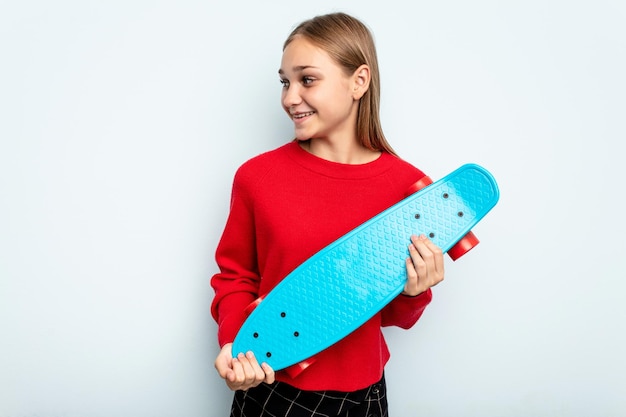 Jeune fille caucasienne patineuse isolée sur fond bleu