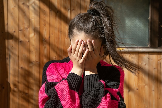 Une jeune fille caucasienne qui se couvre le visage.