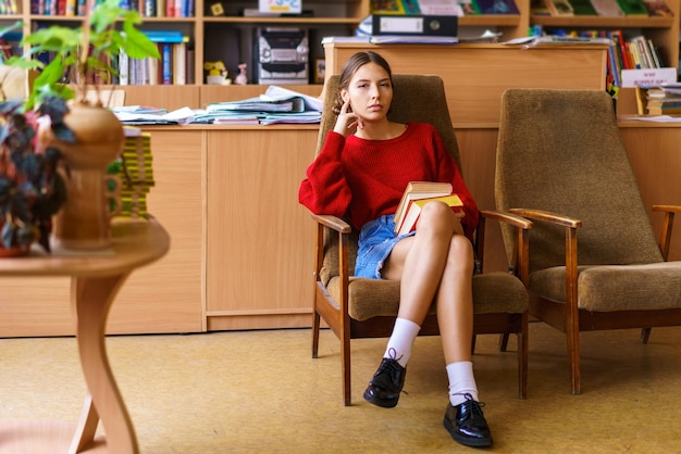 Une jeune fille caucasienne s'intéresse à la lecture assise dans une bibliothèque