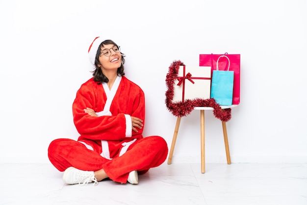 Jeune fille célébrant Noël assis sur le sol isolé sur blanc bakcground heureux et souriant