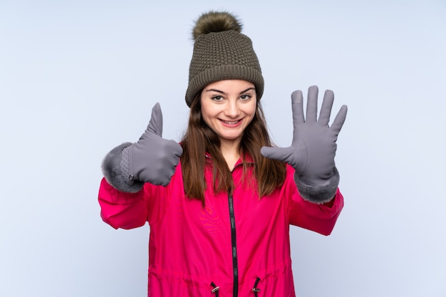 Photo jeune fille avec un chapeau d'hiver sur bleu en comptant six avec les doigts