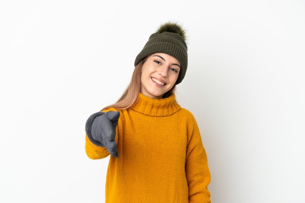 Jeune fille avec chapeau d'hiver isolé sur blanc se serrant la main pour conclure une bonne affaire