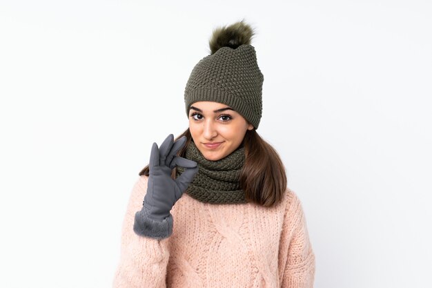 Jeune fille avec un chapeau d'hiver montrant un signe ok avec les doigts