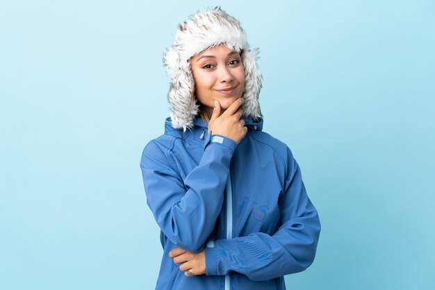 Jeune fille, à, chapeau hiver, sur, mur bleu, rire