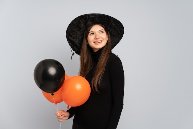 Jeune fille avec chapeau noir et robe noire tenant des ballons