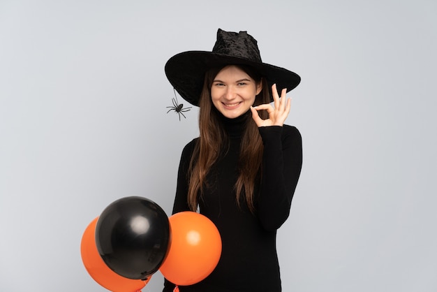 Jeune fille avec chapeau noir et robe noire tenant des ballons