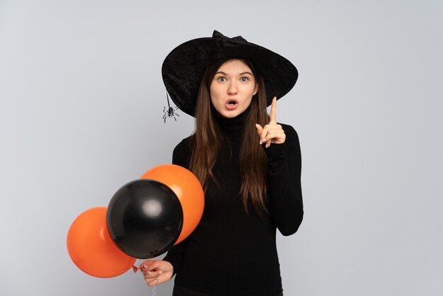 Jeune fille avec chapeau noir et robe noire tenant des ballons