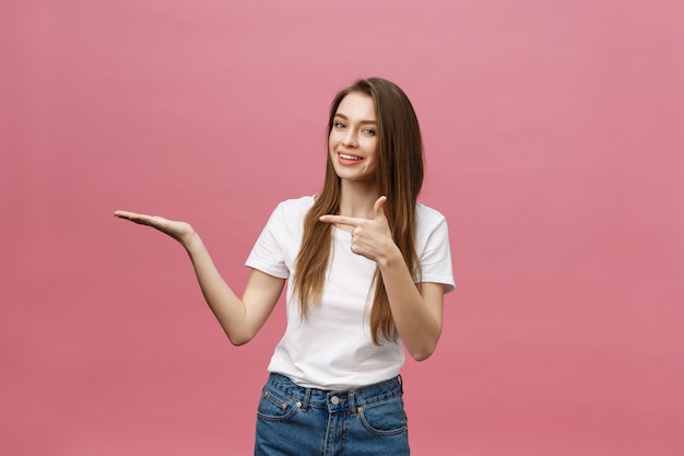 Jeune fille avec une chemise blanche pointant la main sur le côté pour présenter un produit