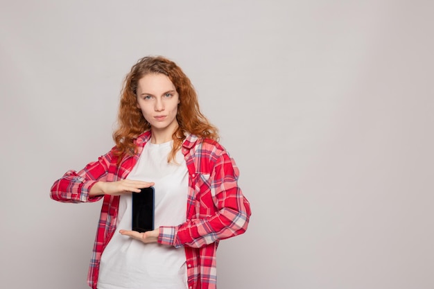 Une jeune fille en chemise à carreaux avec un téléphone sur fond clair