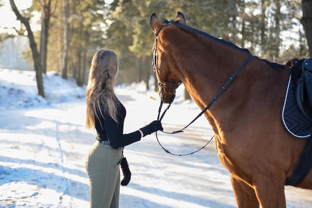 Jeune fille à cheval sur la route forestière d'hiver.