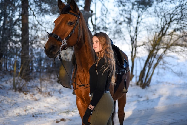 Jeune fille à cheval sur la route forestière d'hiver.