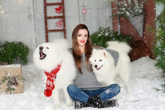 Une jeune fille avec un chien près du sapin de Noël