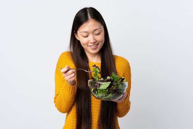 Jeune fille chinoise sur blanc isolé tenant un bol de salade avec une expression heureuse