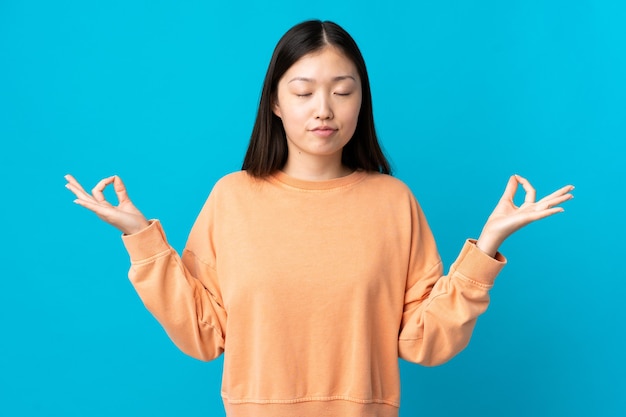 Jeune fille chinoise sur bleu en pose zen