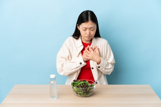 Jeune fille chinoise mangeant une salade ayant une douleur dans le cœur