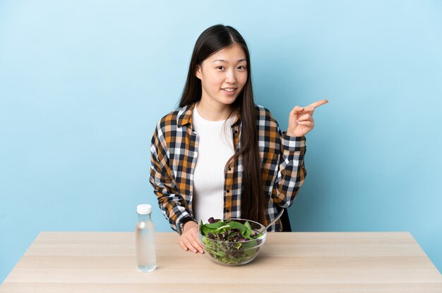 Jeune fille chinoise mangeant une salade du doigt sur le côté