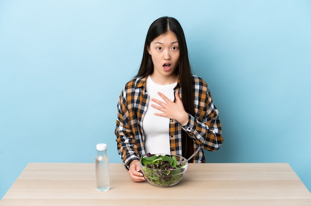 Jeune fille chinoise mangeant une salade surpris et choqué tout en regardant à droite