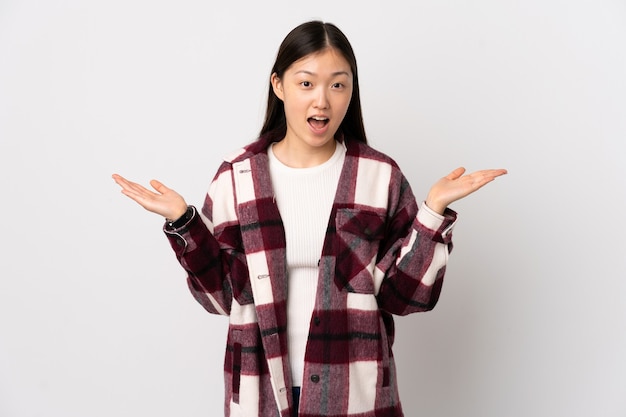 Jeune fille chinoise sur un mur blanc isolé avec une expression faciale choquée