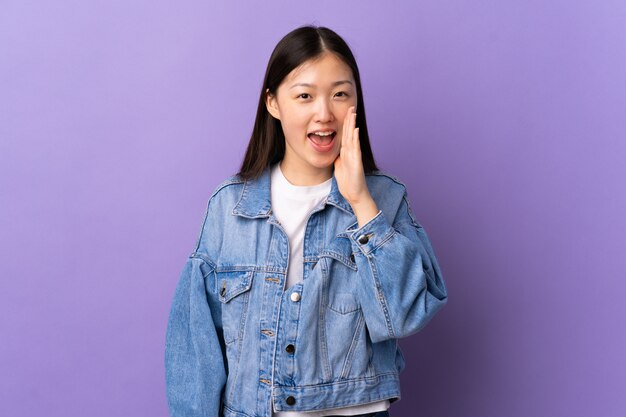 Jeune fille chinoise sur mur violet criant avec la bouche grande ouverte