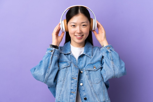 Jeune fille chinoise sur la musique d'écoute violet isolé