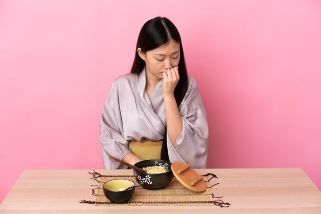 Jeune fille chinoise portant un kimono et manger des nouilles ayant des doutes