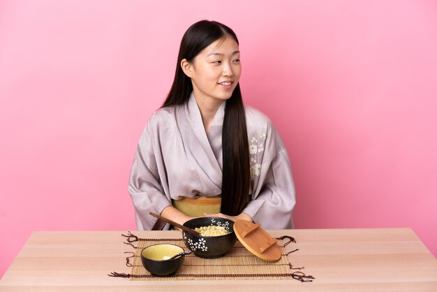 Jeune fille chinoise portant un kimono et manger des nouilles à côté