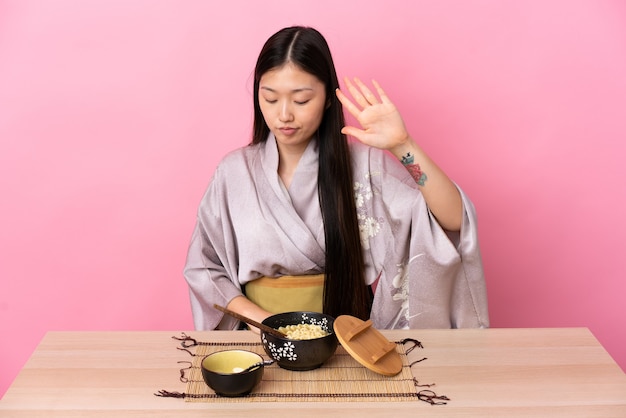 Jeune fille chinoise portant un kimono et manger des nouilles faisant le geste d'arrêt et déçu