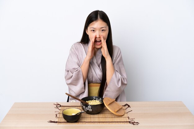 Jeune fille chinoise portant un kimono et manger des nouilles isolées