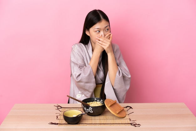 Jeune fille chinoise portant un kimono et manger des nouilles isolées