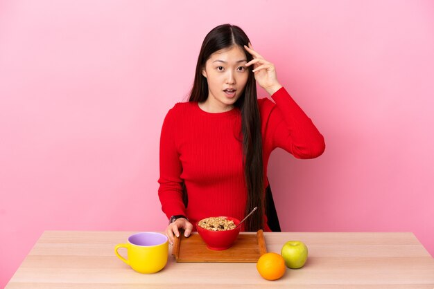 Une jeune fille chinoise prenant son petit déjeuner dans une table a réalisé quelque chose et a l'intention de la solution