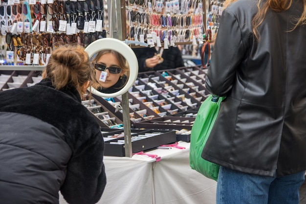 Une jeune fille choisissant des lunettes de soleil sur un marché aux puces