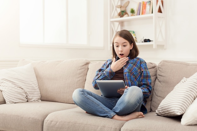 Jeune fille choquée avec tablette à la maison