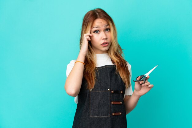 Jeune fille de coiffeur sur fond bleu isolé en pensant à une idée