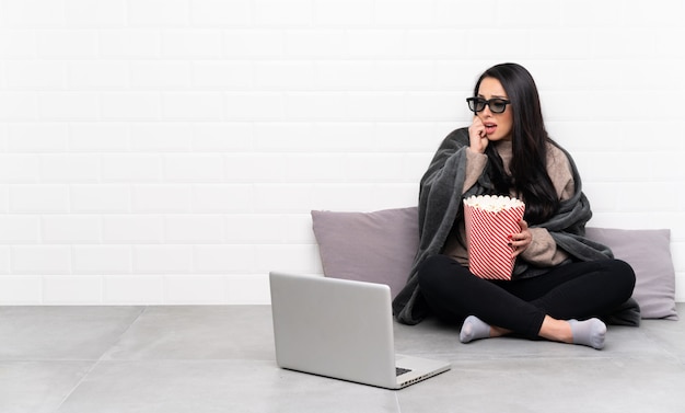 Jeune fille colombienne dans une pièce avec des lunettes 3d et tenant un grand seau de pop-corn