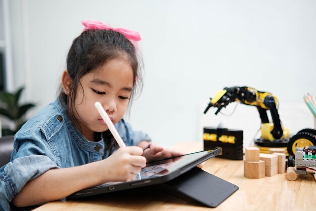 Une jeune fille concentrée en denim utilisant un stylet pour dessiner sur une tablette numérique qui embrasse la technologie