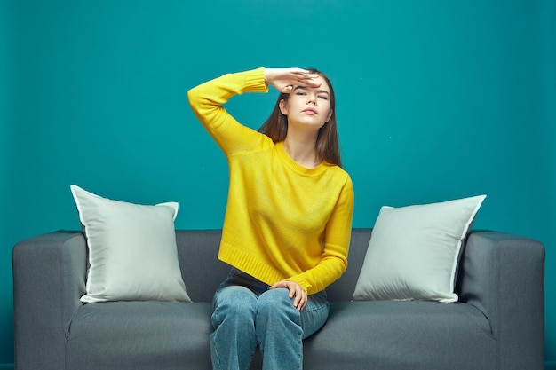 Jeune fille concentrée avec impatience avec la main sur le front à la recherche d'attente assis sur le canapé avenir