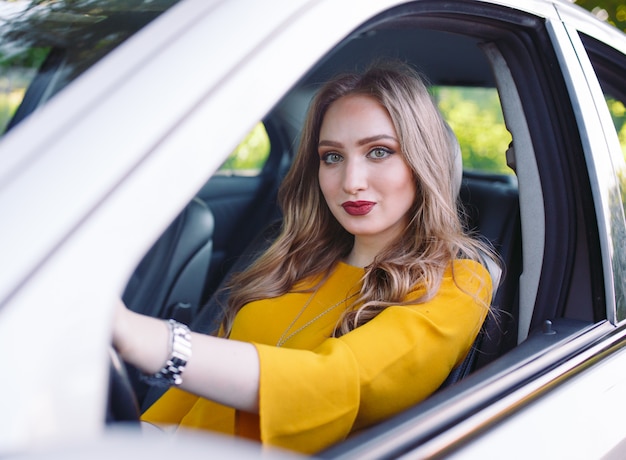 Une jeune fille conduit une voiture.