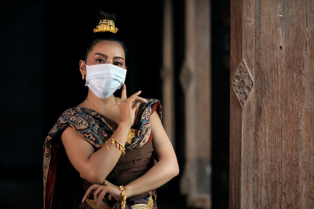 La jeune fille en costume national thaïlandais portant un masque, dansant en position fermée. Prévention des coronavirus