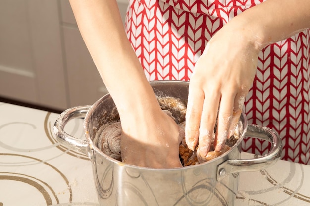 Une jeune fille cuisine dans la cuisine tamise la farine pour dorer la pâte