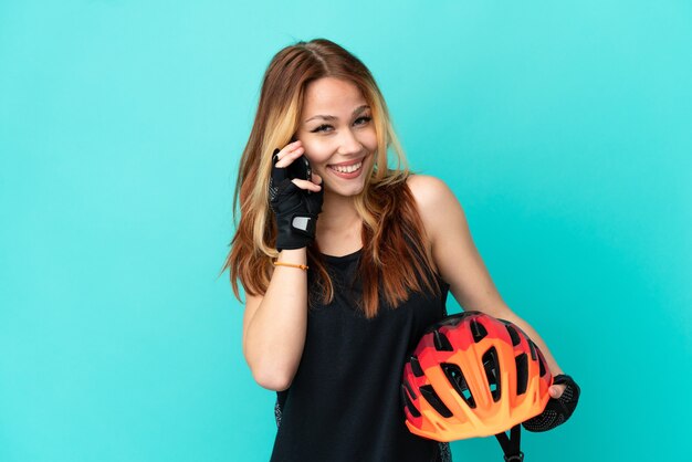 Jeune Fille Cycliste Sur Fond Bleu Isolé Gardant Une Conversation Avec Le Téléphone Portable Avec Quelqu'un