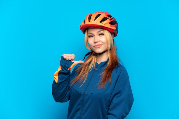 Jeune fille cycliste isolée sur fond bleu fier et satisfait de lui-même